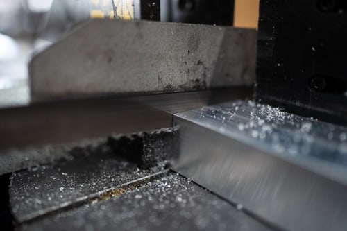 Metallbandsäge schneidet ein Aluminiumprofil, Späne liegen auf der Oberfläche.