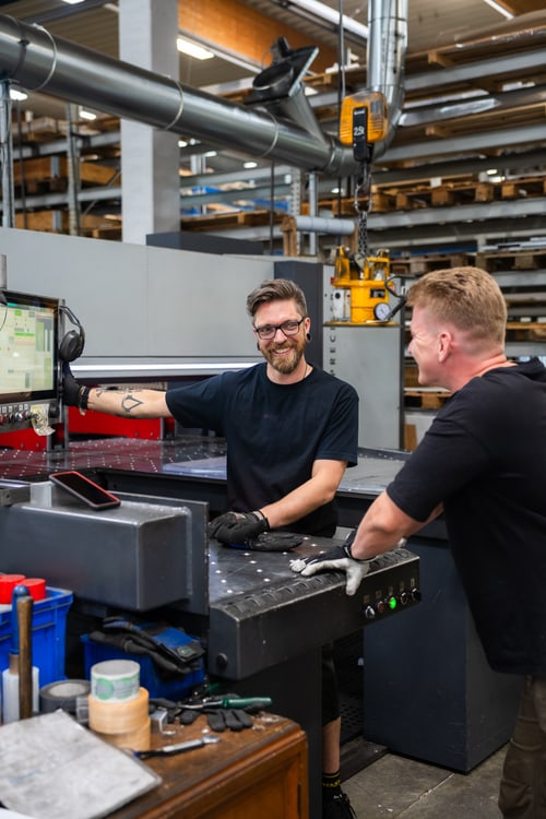 Zwei Mitarbeiter arbeiten an der Steuerung einer Bearbeitungsmaschine.
